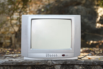 An old silver TV set stands in the woods. Vintage TVs 1980s 1990s 2000s. 