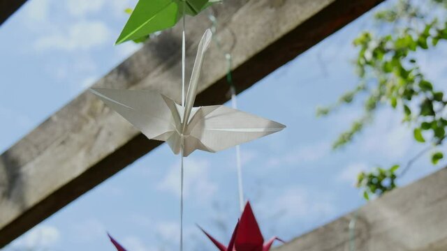 White paper crane on string sway in the wind. Japanese origami figure in park