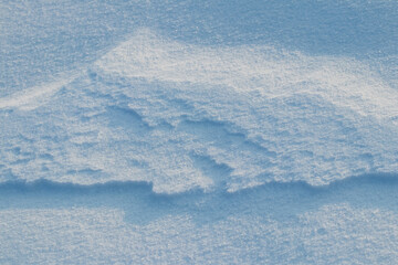 Snowy background, snow-covered surface of the earth after a blizzard in the morning in the sunlight with distinct layers of snow