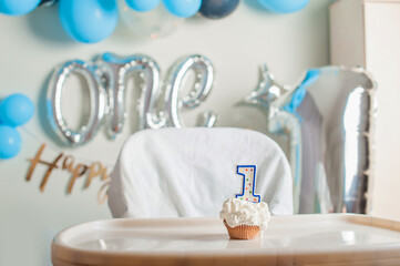 Yummy birthday cupcake with candle for first year of birth. Boy's anniversary table decor.