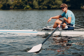 Sportsman single scull man rower rowing on boat. Relaxing after competition