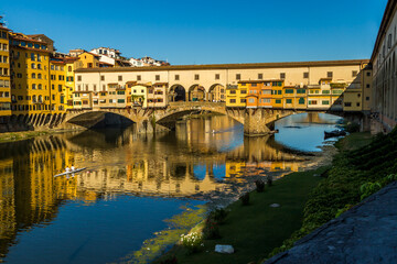 Rowers out on the River Arno during a lovely sunny morning in Florence, Italy, with the historic...