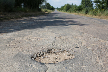 A large deep pit on an asphalt road.