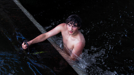 A young brunette guy in the water