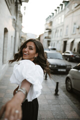 Naklejka na ściany i meble Joyful young brunette with long wavy hair, tanned body, big brown eyes in vintage clothes and accessories posing on steer outstretched, smiling and looking into camera