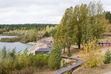 Autumn river beach with wooden paths,  wind shakes trees