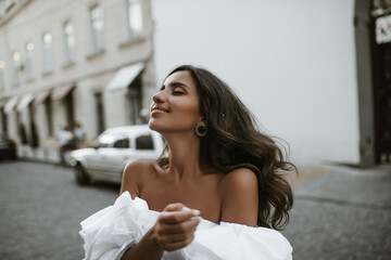 Charming young brunette with bronzed body in white off-shoulder blouse and vintage accessories,...