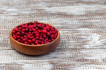 Bowl of fresh cranberry on wooden background, horizontal, copy space