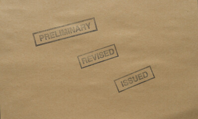 the words preliminary, revised, and issued stamped in dark ink on craft paper
