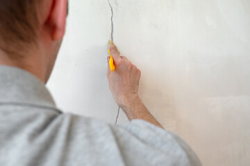 Construction man worker repairing a crack wall of a home, plastering cement on wall. Builder...