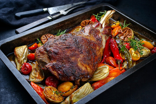 Traditional barbecue lamb shoulder with vegetables and chili served as close-up on a rustic metal tray