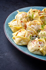 Traditional steamed Kazakh manti garnished with mincemeat and sumah served as close-up on a Nordic design plate