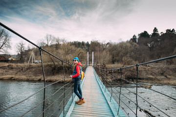 Fototapeta premium A woman walks over the river on a suspension bridge