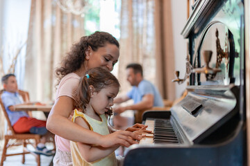 The little girl learns to play the piano skillfully, listens carefully to the instructions of the educator and tries to do everything right.