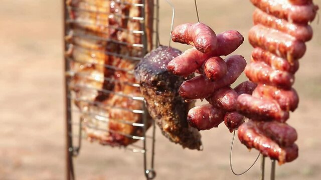 Carne assada no fogo no ch&atilde;o e na lenha.
