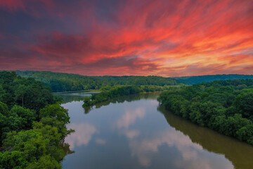  a stunning aerial shot of the still brown waters of the Chattahoochee river surrounded by vast miles of lush green trees with powerful clouds at Roswell Riverwalk Boardwalk in Roswell Georgia - Powered by Adobe
