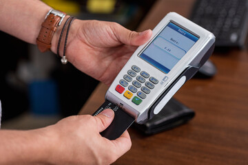 Manos de una persona utilizando una maquina para tarjetas de crédito para cobrar dinero 