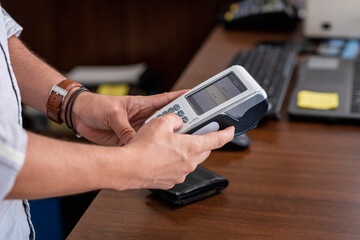 Manos de una persona utilizando una maquina para tarjetas de crédito para cobrar dinero 