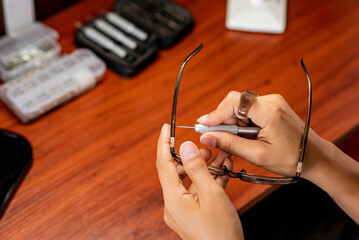 Manos de una mujer reparando lentes con diferentes herramientas 