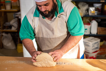 Cocinero masando harina en la mesa para luego cortar la masa con un cuchillo y preparar los...