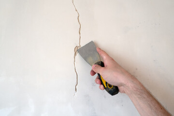 Construction man worker repairing a crack wall of a home, plastering cement on wall. Builder...