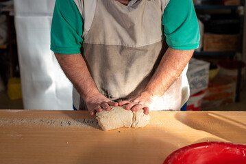 Cocinero masando harina en la mesa para luego cortar la masa con un cuchillo y preparar los...