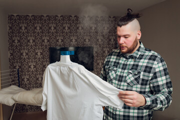 a man puts things in order. holds the garment steamer in his hand and smoothes the jacket after...