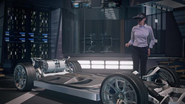 Mockup of Electric Vehicle: Automotive Female Professional Engineer working on design of Electric Car Chassis with Hand Gestures using Futuristic Augmented Reality Headset inside High-tech facility.