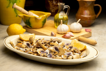 PLATE OF STEAMED CLAMS OR COQUINAS WITH GARLIC, LEMON AND OLIVE OIL READY TO EAT ON THE KITCHEN...