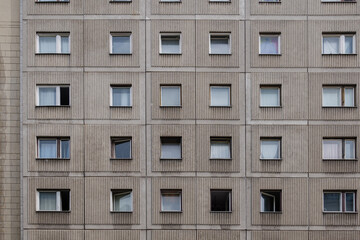 Outdoor sunny street front view of typical modern residence or apartment in city of Europe with rough raw concrete facade, rectangular windows and doors.