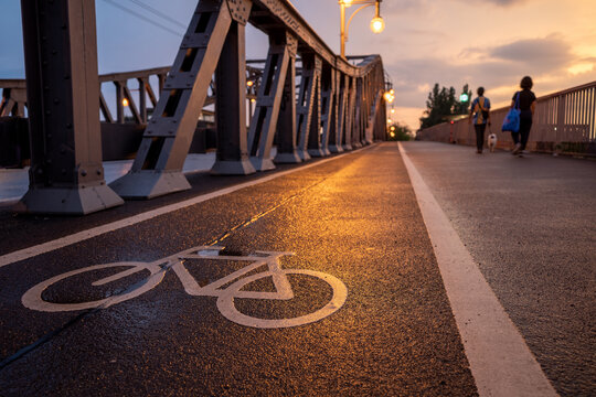 Selected focus view of white bicycle symbol on bicycle lane beside the road on Bösebrücke steel bridge at Bornholmer in Berlin, Germany during twilight sky. Cycling friendly city concept in Europe. 