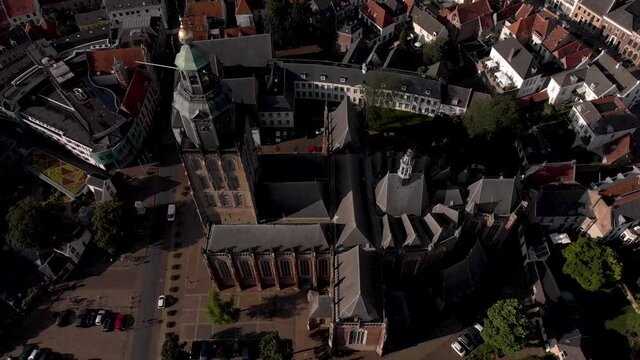 Backwards aerial movement revealing the wider town surrounding of Walburgiskerk cathedral in medieval Hanseatic city Zutphen in The Netherlands. Dutch urban landscape seen from above.