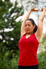 Adult asian woman doing yoga in nature, doing stretching and flexibility exercises, yoga class for adult women