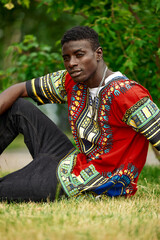 An African man in South African national clothes, a black young man resting in a park in national...