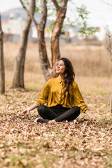 girl sitting among dry leaves smiles