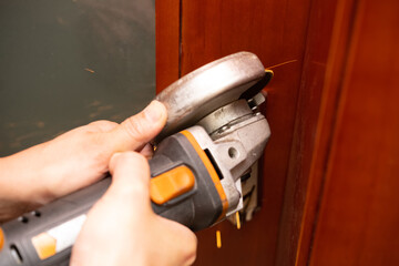man cutting out a door lock by a grinder
