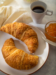 Delicious and nutritious traditional breakfast - croissants, jam and a cup of coffee. White silk tablecloth. Close-up. Careful viewing. Low angle view. Restaurant, cafe, hotel, home cooking.