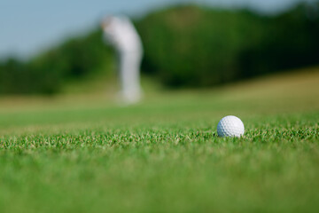 golf ball with golfer blur in background.