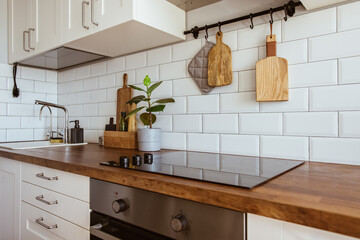 Kitchen brass utensils, chef accessories. Hanging kitchen with white tiles wall and wood...