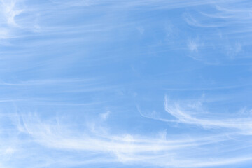 Peaceful wispy white clouds against a clean blue sky as a nature background

