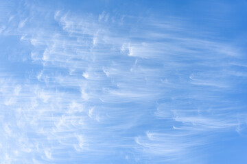 Peaceful wispy white clouds against a clean blue sky as a nature background
