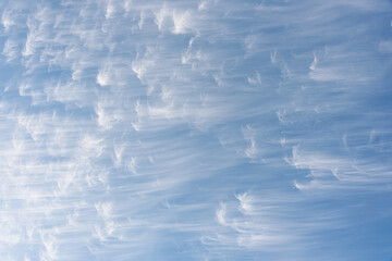 Peaceful wispy white clouds against a clean blue sky as a nature background
