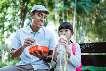 Obraz premium lovely father feed his daughter in the park