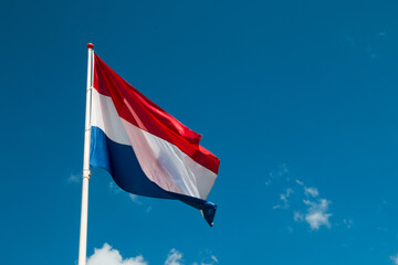 flag of the netherlands moving in a blue sky - obrazy, fototapety, plakaty