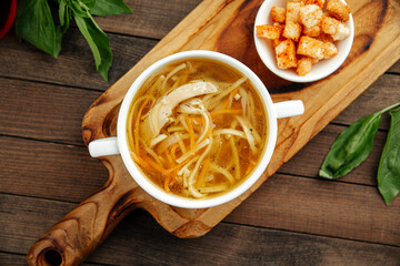 Chicken noodle soup with croutons on wooden background