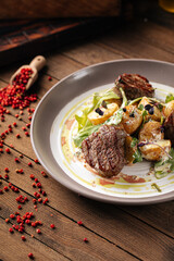Plate of gourmet fillet mignon steaks with potatoes on a wooden background