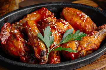 Cast iron plate of fried chicken wings in teriyaki sauce