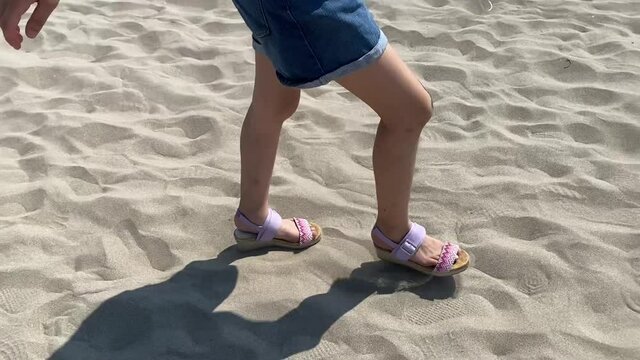 砂浜をサンダルで歩く女の子　小学生　子供