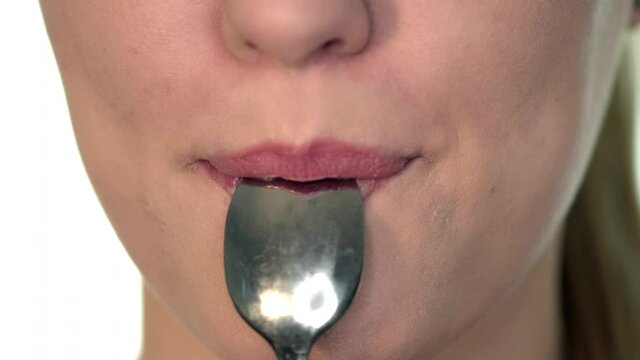 A sexy woman with intention to seduce remove the spoon in her mouth slow by slow and put on a quiet smile. A woman with sexy lips show a seduction expression.