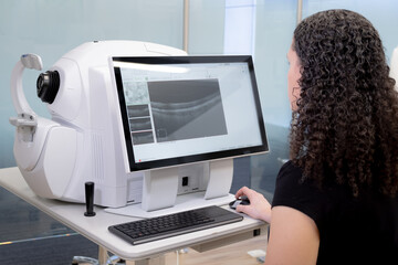 Woman doctor specialist in vision problems sitting in front of ophthalmic diagnostic machine in a...